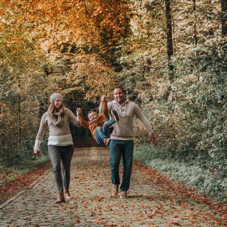 Shooting photo de famille naturelle en automne avec les parents et un enfant qui jouent belgique