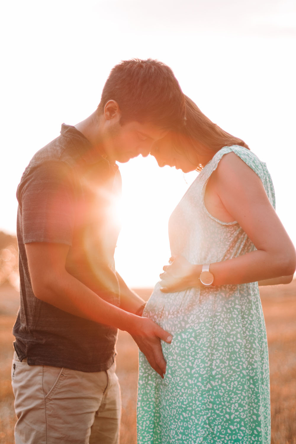 Photo de grossesse un couple regarde le ventre de la femme enceinte dans le soleil couchant dans un champ de blé en Belgique Nivelles